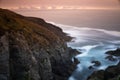 Cliff with orange horizon at sunset and blue sea