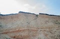 A cliff where soil layers are visible, and above it sky and clouds Royalty Free Stock Photo