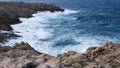 cliffs of Menorca, Spain. Waves of blue sea hurl themselves on the rocks