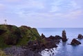 The cliffs of Supjikoji in Jeju Island, South Korea with white lighthouse and candle shaped rock in the sea.