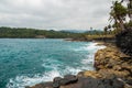 Cliffs on a tropical shore with palm trees and pristine blue sea Royalty Free Stock Photo