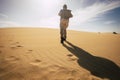 Climate change concept with man walkling with backpack in. arid sand desert under the warm sun and no water - danger for the