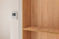 Climate control panel on the wall in a room with wooden built-in furniture with shelves