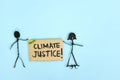Climate justice concept. People stick figures protesting while holding a carton placard.