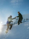 Climber assists another climber on the slope of snowy mountains Royalty Free Stock Photo