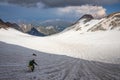 Climber crossing a glacier surrounded by mountains, with snow-capped mountains and a storm in the background