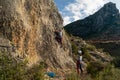 Climber girl with all the climbing equipment belaying a boy who starts to climb a rock wall at sunset Royalty Free Stock Photo