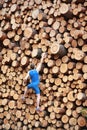 Climber going up the large pile of cut wooden logs