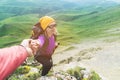 A climber helps a young mountaineer woman reach the top of the mountain. A man gives a helping hand to a woman. View