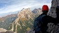 Climber man in a helmet on the top of a mountain looking into the horizon view from the back