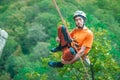 A climber in an orange shirt swinging on a rope