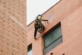 Climber painter suspended from ropes and harnesses paint the exterior of an apartment building