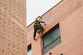 Climber painter suspended from ropes and harnesses paint the exterior of an apartment building