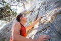 Climber in red t-shirt climbs a gray rock. A strong hand grabbed the lead, selective focus. Strength and endurance, climbing