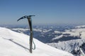 Climber`s ice ax stuck on a snowy slope, winter mountain climbing