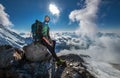 Climber in a safety harness, helmet, and high mountaineer boots with picturesque clouds background sitting at 3600m altitude on Royalty Free Stock Photo