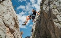 Climber teenager boy in protective helmet abseiling from vertical cliff rock wall using rope Belay device, climbing harness in Royalty Free Stock Photo