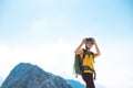 climber on top of the mountain takes a photo. Girl with a backpack and hard hat in the mountains. Woman traveler takes a photo on