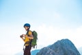 climber on top of the mountain takes a photo. Girl with a backpack and hard hat in the mountains. Woman traveler takes a photo on