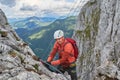 Climber winking towards the camera, while changing lanyards on via ferrata Intersport, Donnerkogel mountain, Austria