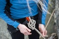 Climber woman in safety harness tying rope in bowline knot