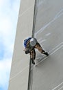 Climber worker hanging on ropes to repair building service on high rise building