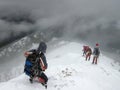 Climbers entering a dark abyss during winter blizzard in the mountain Royalty Free Stock Photo