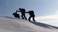 Climbers hand in hand climb to top of a snowy mountain. the team of travelers in winter go to their goal of overcoming Royalty Free Stock Photo