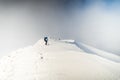 Climbers navigating through snow-covered peaks under a cloudy sky in the mountains Royalty Free Stock Photo