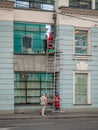 Climbers with stairs wash windows in building. Workers in branded overalls and special equipment for high-altitude work.