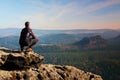 Climbing adult man at the top of rock with beautiful aerial view of the deep misty valley bellow Royalty Free Stock Photo