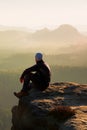 Climbing adult man at the top of rock with beautiful aerial view of the deep misty valley bellow Royalty Free Stock Photo