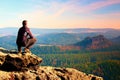 Climbing adult man at the top of rock with beautiful aerial view of the deep misty valley bellow Royalty Free Stock Photo