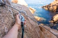 Climbing grips details young man& x27;s hand on rocks over the sea with rope and helmet. Royalty Free Stock Photo
