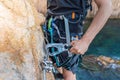 Climbing grips details young man& x27;s hand on rocks over the sea with rope and helmet. Royalty Free Stock Photo