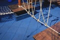 Climbing rope with vintage outdoor wooden playground equipment on blue rubber tile floor in public park area Royalty Free Stock Photo