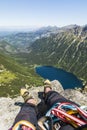 Climbing shoes on the feet of a climber during a rest at the top after climbing. View from Mnich to Lake Morskie Oko and surroundi