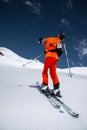 Ascent of a skier with a backpack in a mask and sunglasses on skis with poles to go uphill for freeride and backcountry