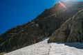 Climbing team roping up woman and man dressed high altitude mountaineering clothes with backpacks walking by snowy slope in the Royalty Free Stock Photo