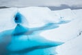 Climbing up out of a canoe, an ice climber leads a steep line near the entrance of a massive ice cave flooded by a blue lake