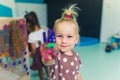 Cling film painting at the nursery school. Happy smiling blonde toddler girl showing her painted colorful palm. Art Royalty Free Stock Photo