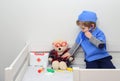 Clinic. Adorable child dressed as doctor playing with toy. Health exam by young medical worker. Educative and