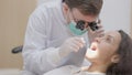 In the clinic, a dentist cleans the teeth of a patient