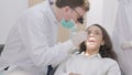 In the clinic, a dentist cleans the teeth of a patient