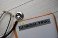 Clinical Trial text with document brown envelope and stethoscope isolated on office desk