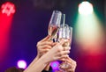 Clinking glasses of champagne in hands on bright lights background. Royalty Free Stock Photo