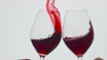 Clinking raising red beverage vessels closeup. Rose wine splashing over the edge Royalty Free Stock Photo