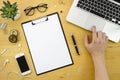 Clip board mockup with man hand and notebook, smartphone, office accessories on wood desk background. finger on the