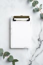 Clipboard with blank paper and eucalyptus branches on marble desk. Flat lay, top view. Wedding checklist concept Royalty Free Stock Photo