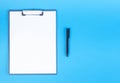 Clipboard with blank sheet of white paper and pen on blue background, place for text. Royalty Free Stock Photo